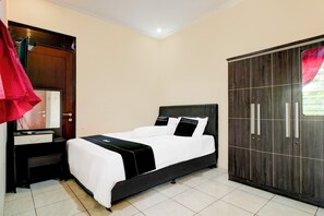 A bedroom with a bed, a nightstand, a wardrobe, and a mirror. - Hotel O Griya Cewang Syariah (Bekasi)