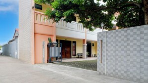 Un edificio con entrada pavimentada, camino de acceso con portón y pared de azulejos.