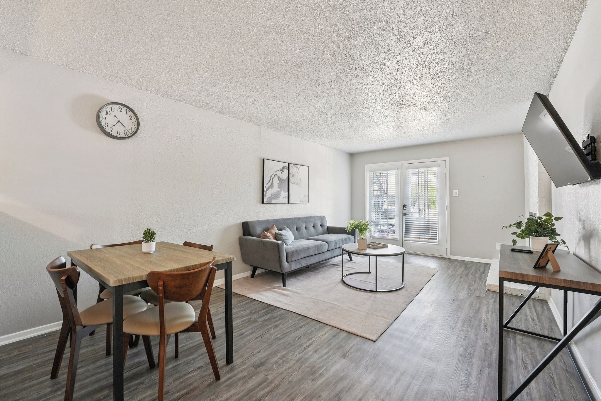 Un salon moderne avec un canapé gris, une table à manger en bois et une petite table basse.