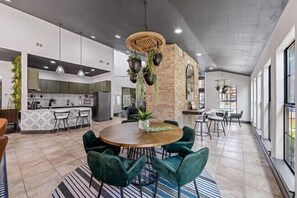Een ruime keuken met moderne apparatuur, een eethoek met een ronde tafel en stoelen, en een groot raam dat zorgt voor daglicht.