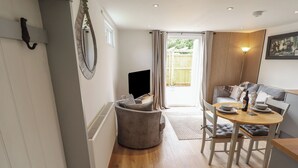 A modern living room with a sofa, a round table, and a television. - Pear Tree Lodge (Alford)