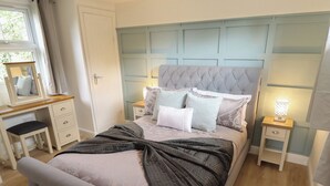 A bedroom with a bed, a bedside table, a nightstand, a dresser, a mirror, and a window. - Pear Tree Lodge (Alford)