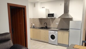 Een kleine keuken met een wasmachine, magnetron en een inbouwafzuigkap.