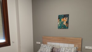 Een slaapkamer met een bed, een hoofdeinde, een raam met jaloezieën en een schilderij aan de muur.