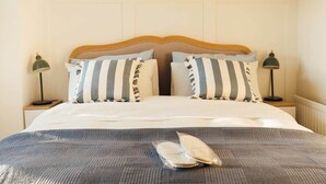 A neatly made bed with striped pillows, a headboard, and bedside lamps. - No. 66 Chapel Street (Cookstown)