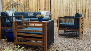 A wooden outdoor seating area with a sofa, two chairs, and a small table, surrounded by a wooden fence and gravel ground. - No. 66 Chapel Street (Cookstown)