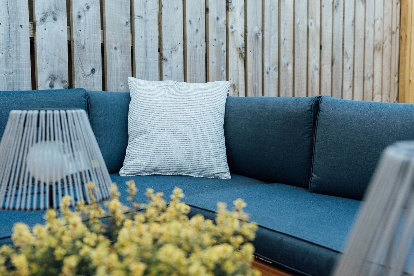 Ein blaues Sofa mit einem weißen Kissen und einer Lampe davor.