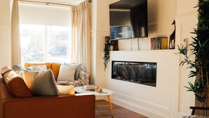 A living room with a sofa, a fireplace, a television, and a bookshelf. - No. 66 Chapel Street (Cookstown)