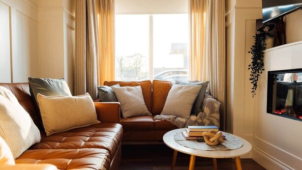A living room with a brown leather sofa, a round coffee table, and a fireplace. - No. 66 Chapel Street (Cookstown)