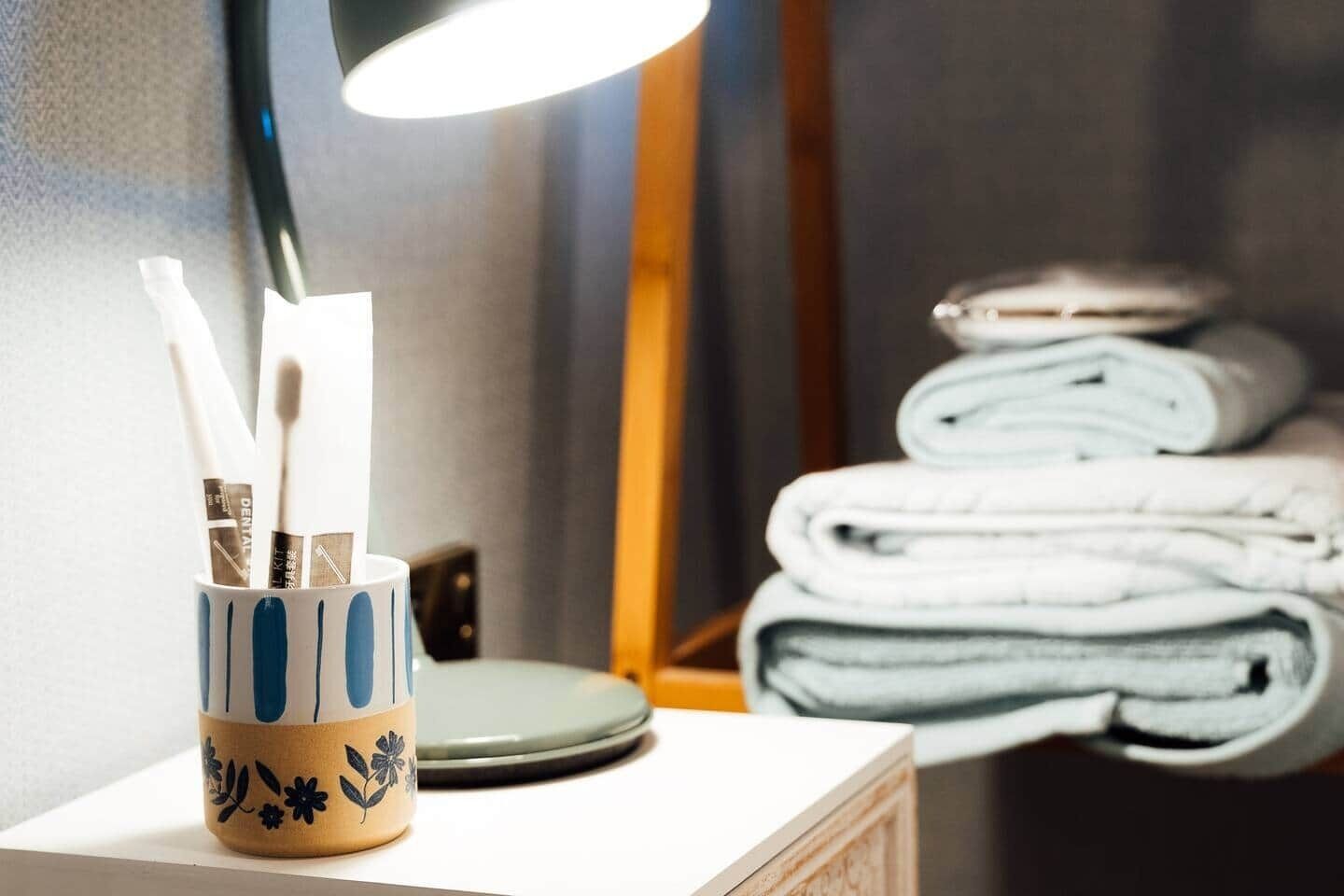 Une salle de bain avec un lavabo, des brosses à dents et une pile de serviettes.