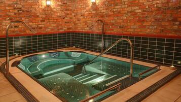 A hot tub with a brick wall background and tiled flooring.
