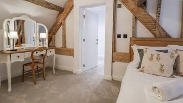 A bedroom with a wooden bed, a desk with a mirror, and a door leading to another room.