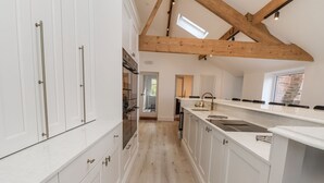 Una cocina moderna con armarios blancos, techo de madera y vistas al área de comedor contigua.