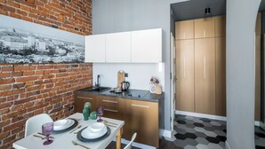 Une cuisine moderne avec des armoires blanches, un plan de travail noir et un mur en briques.