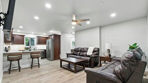 A modern living room with a leather sofa, a coffee table, and a dining area with bar stools. - The White House | Unit 3 (Shaver Lake)