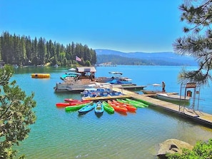 A lakeside dock with canoes and a small building, surrounded by trees and a clear sky. - The White House | Unit 3 (Shaver Lake)