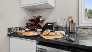 A kitchen with a marble countertop, a wine rack, a toaster, and various food items.