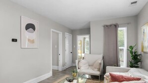 A modern living room with a glass coffee table, a white sofa, and a beige sofa.