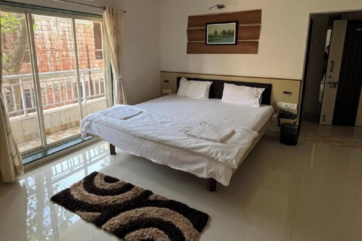Quarto com cama, ventoinha no teto, quadro na parede e janela com vista para um muro de tijolos.