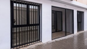 A building with three black metal gates on white walls. - Lôla Suites by Concept (València)