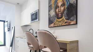 A modern kitchen with a wooden countertop, two bar stools, and a painting on the wall. - Lôla Suites by Concept (València)