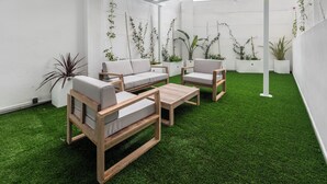 A modern outdoor patio with wooden furniture and green artificial turf. - Lôla Suites by Concept (València)