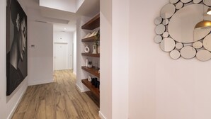 A modern hallway with a wooden floor, a large mirror with circular frames, and a poster on the left wall. - Lôla Suites by Concept (València)