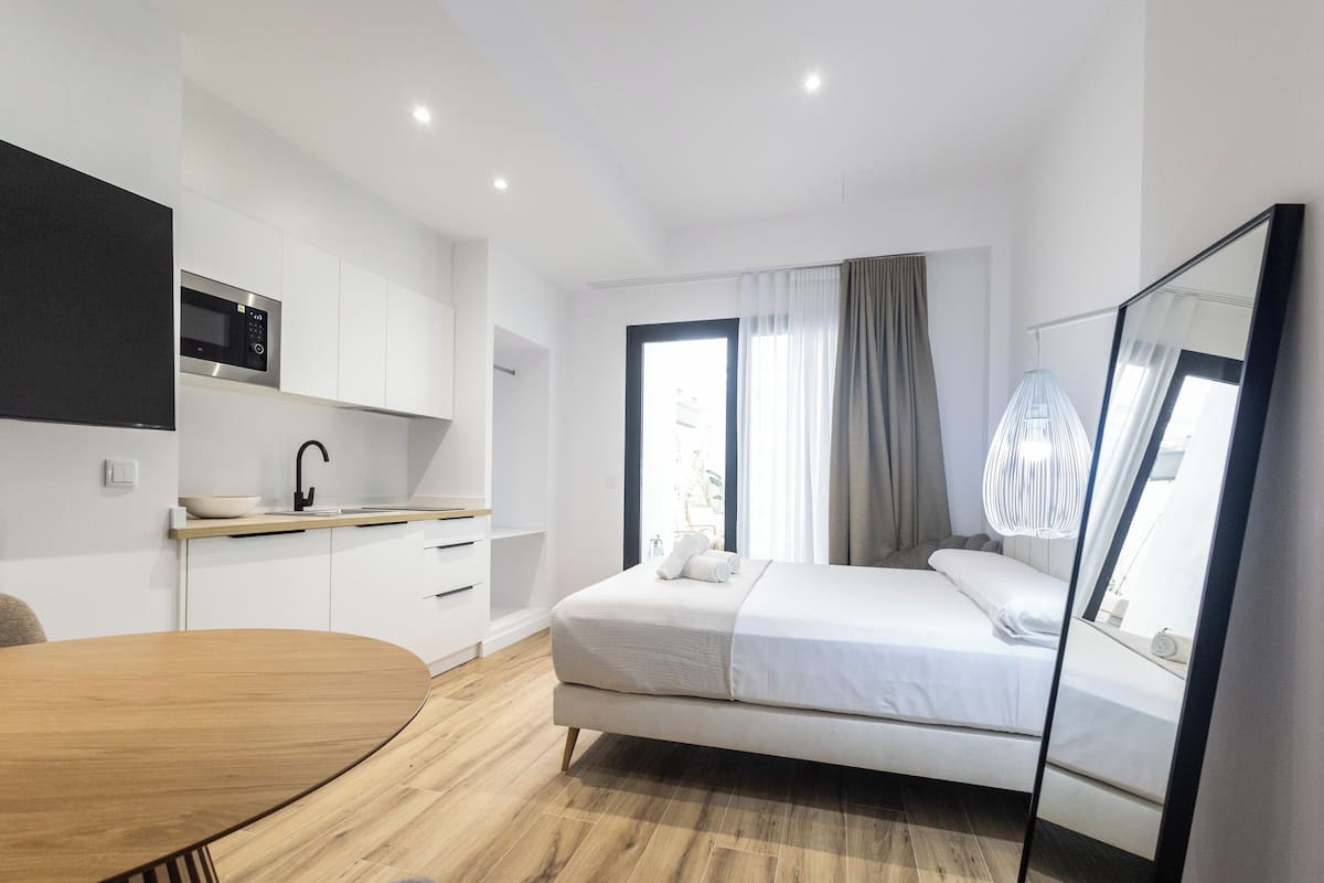 Une chambre à coucher moderne, avec un lit, une table de chevet, un miroir et une vue sur l’extérieur.