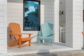 Two Adirondack chairs, one orange and one teal, positioned on a porch with a view of a house through a window. - NEW "Bikinis & Martinis" Private Pool,Gulf Views, Bikes, LSV (Santa Rosa Beach)