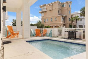 A pool area with a hot tub, outdoor chairs, and a barbecue grill.