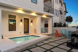 A two-story building with a covered patio area featuring a swimming pool, outdoor seating, and a gas cylinder.