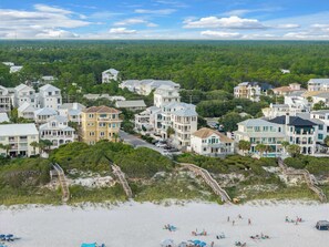 A coastal residential area with beachfront properties, a sandy beach, and a forested background.