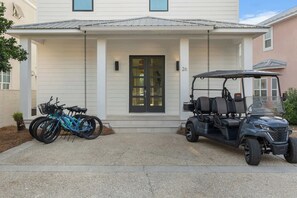 A house with a porch, two bicycles, and a golf cart parked in front. - NEW "Bikinis & Martinis" Private Pool,Gulf Views, Bikes, LSV (Santa Rosa Beach)