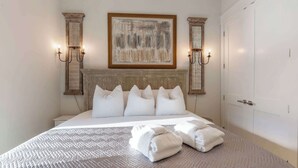 A neatly made bed with a textured bedspread, a headboard with a decorative panel, and a painting above it. - NEW "Bikinis & Martinis" Private Pool,Gulf Views, Bikes, LSV (Santa Rosa Beach)