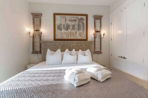 A neatly made bed with a textured bedspread, a headboard with a decorative panel, and a painting above it. - NEW "Bikinis & Martinis" Private Pool,Gulf Views, Bikes, LSV (Santa Rosa Beach)