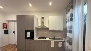 A modern kitchen with grey cabinets, a stainless steel stove, and a tiled backsplash. - La Dimora di Sara - Comfort and Privacy at 10 Minutes from Termini (Roma)