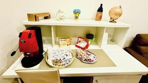 A desk with a red coffee maker, a basket of coffee pods, a red tissue box, and a globe. - La Dimora di Sara - Comfort and Privacy at 10 Minutes from Termini (Roma)