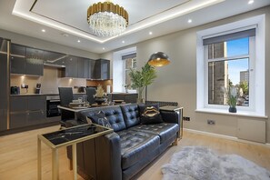 A modern living room with a leather sofa, a dining table, and a chandelier. - Jackson Terrace HL6 - Grampian Lettings (Aberdeen)
