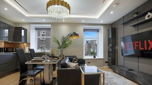 A modern living room with a dining area, a TV, and a chandelier. - Jackson Terrace HL6 - Grampian Lettings (Aberdeen)