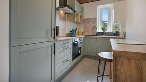 A modern kitchen with grey cabinets, a wooden ceiling, and a window providing natural light. - Abbey Place Apartment | Grampian Lettings (Aberdeen)