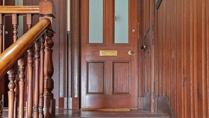 A wooden staircase leading to a door with a brass plate, a glass panel, and a brass doorknob. - Abbey Place Apartment | Grampian Lettings (Aberdeen)