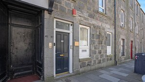 Un edificio de piedra con puertas numeradas, una puerta roja y una puerta negra.