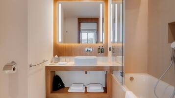 A modern bathroom with a wooden vanity, a large mirror, and a glass shower enclosure.
