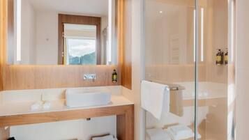 A modern bathroom with a wooden vanity, a large mirror, and a glass-enclosed shower area.
