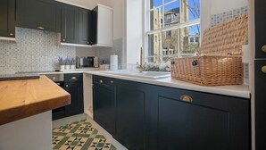 Une cuisine avec des meubles de couleur sombre, un plan de travail blanc, un four à micro-ondes et un panier en osier posé sur le plan de travail.