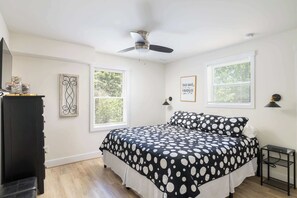 A bedroom with a bed, a ceiling fan, two windows with blinds, a dresser, and a bedside table. - This Home Has It All! Location, Amenities, & More! (Duck)