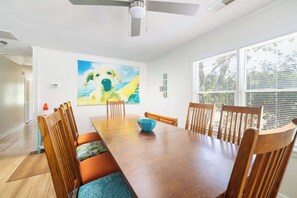 A dining room with a wooden table, chairs, a blue bowl, and a painting of a dog. - This Home Has It All! Location, Amenities, & More! (Duck)