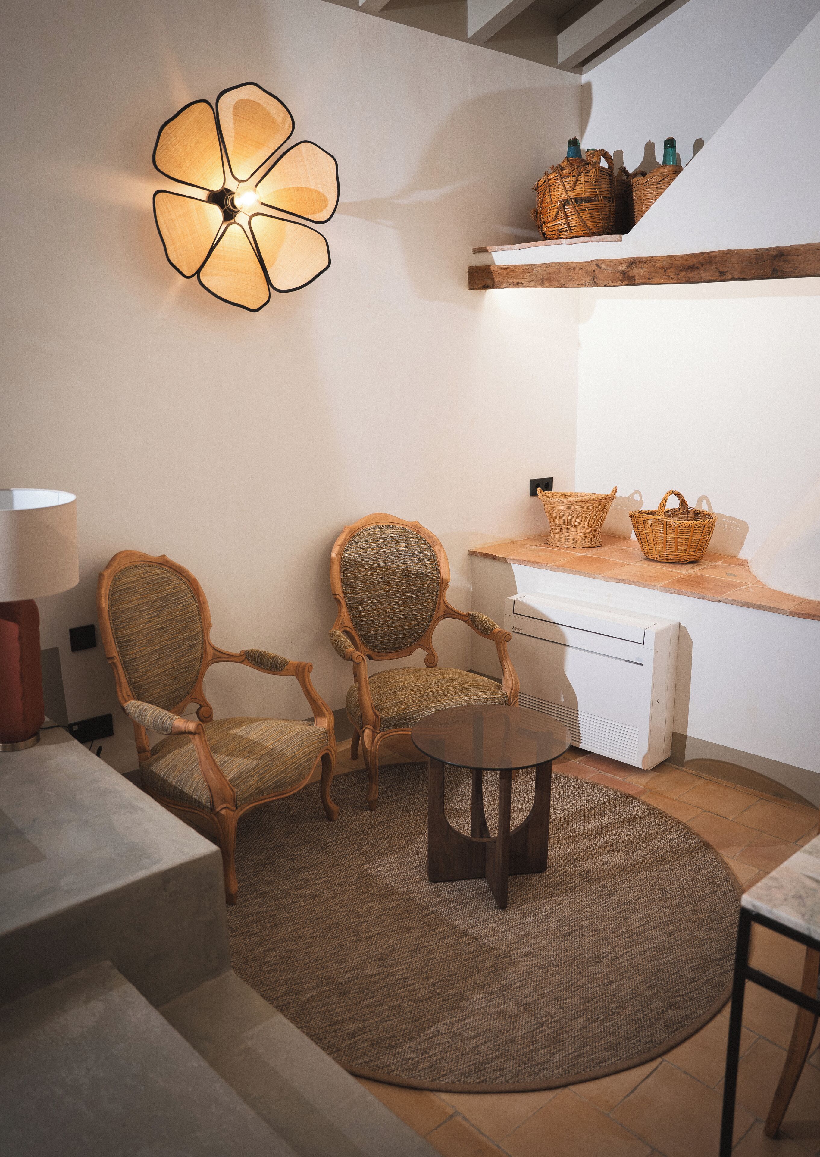 A cozy seating area with two upholstered chairs, a small round table, and a decorative wall light.