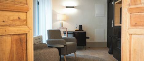 Una habitación acogedora con puerta de madera, una mesita, dos sillas, una lámpara, una cafetera y un lavavajillas.