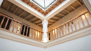 A high-ceilinged atrium with wooden balconies and a skylight. - Hotel Boutique Casona de los Rebolledo (Zújar)